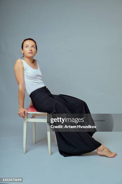 redhead woman, sitting on stool, dressed in wide baggy pants - barefoot redhead ストックフォトと画像