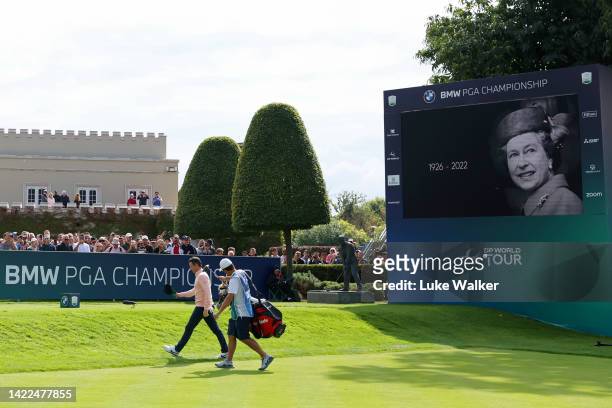 Rory McIlroy of Northern Ireland walks past an LED Screen displaying an image in memory of Her Majesty, Queen Elizabeth II, during Round Two on Day...