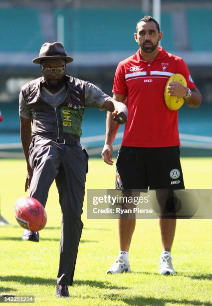 Will.i.am from The Black Eyed Peas kicks and AFL football as Adam Goodes from the Sydney Swans looks on during a young indigenous AFL players clinic...