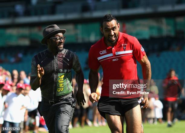 Will.i.am from The Black Eyed Peas runs against Adam Goodes from the Sydney Swans during a young indigenous AFL players clinic at Sydney Cricket...