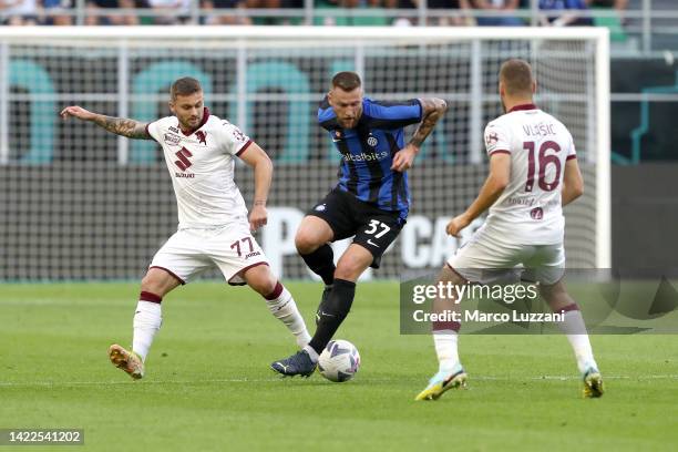 Milan Skriniar of FC Internazionale is challenged by Karol Linetty and Nikola Vlasic of Torino FC during the Serie A match between FC Internazionale...