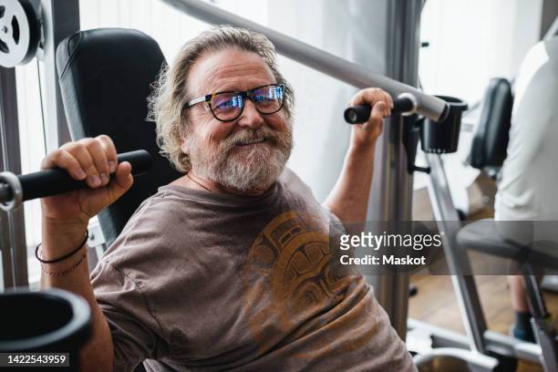 portrait of smiling overweight senior man exercising in gym - bart stock-fotos und bilder