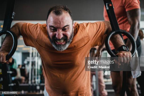 dedicated man exercising with gymnastic rings in heath club - arabische muster stockfoto's en -beelden