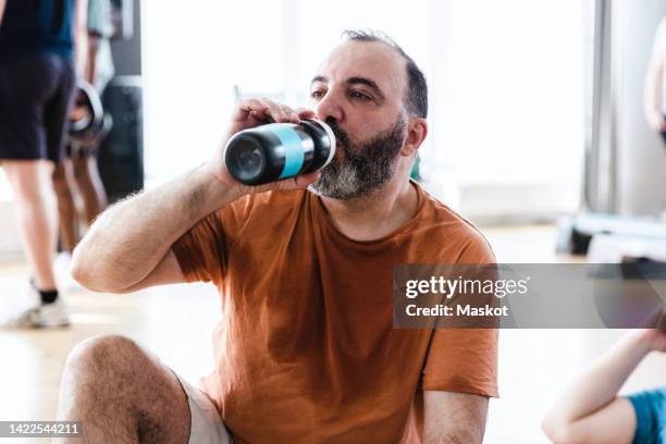 tired man drinking water after exercise class in health club - sweat stain gym stock pictures, royalty-free photos & images