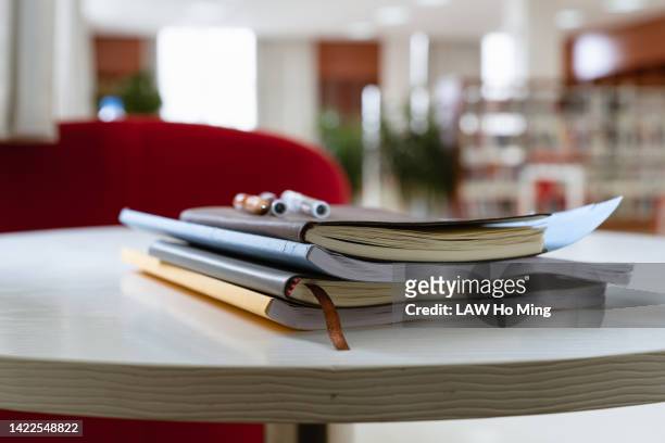 a stack of books on a table in the library - scientific literature stock-fotos und bilder
