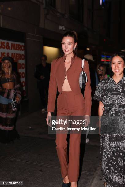 Karlie Kloss is seen wearing a red short blazer jacket, matching red suit pants, silver earrings and white/grey Fendi Baguette bag; Eva Chen is seen...