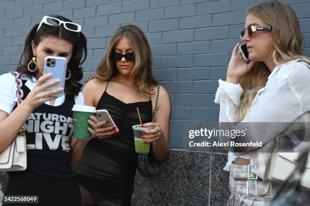 Morgan Rhodes wearing revolve, Tina Peyton wearing a vintage SNL top and Carter Fish wearing verge girl use their mobile phones outside Spring...