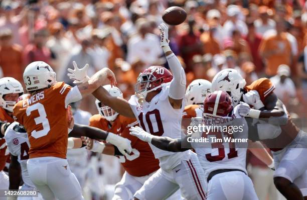 Quinn Ewers of the Texas Longhorns throws a pass under heavy pressure applied by Henry To'oTo'o of the Alabama Crimson Tide in the first half at...