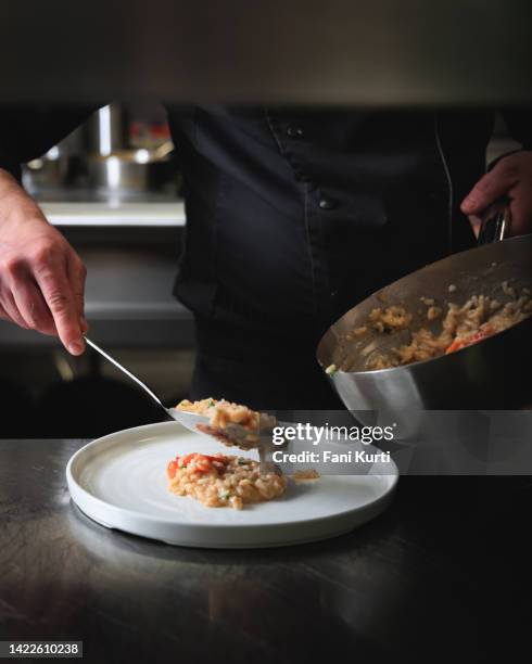 zubereitung und servieren von meeresfrüchte-risotto - risotto stock-fotos und bilder