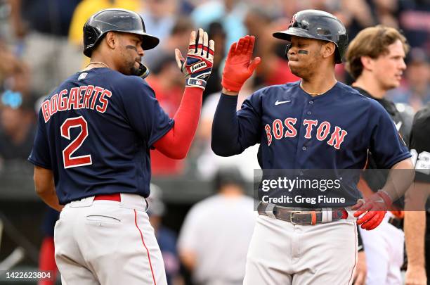 Rafael Devers of the Boston Red Sox celebrates with Xander Bogaerts after hitting a Grand Slam in the first inning against the Baltimore Orioles at...