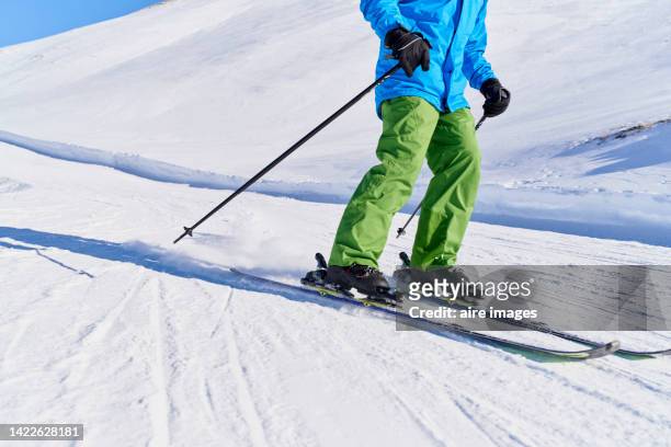 young man in sports equipment skiing down a mountain on a sunny day with clear blue skies - nur erwachsene stock-fotos und bilder