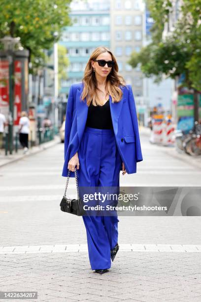 Alexandra Lapp wearing a blue suit by Alexander McQueen, a black v-neck top by, Alexander McQueen, a black bag by Balenciaga, black booties with...