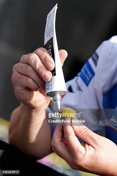 Crew member applies glue to a lugnut proior to the start of the NASCAR Sprint Cup Series Goody's Fast Relief 500 at Martinsville Speedway on April 1,...