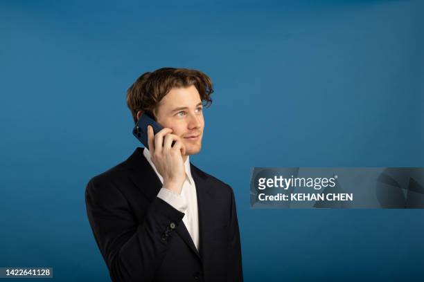 studio shoot with businessman using smartphone with blue backdrop - new zealand money photos et images de collection