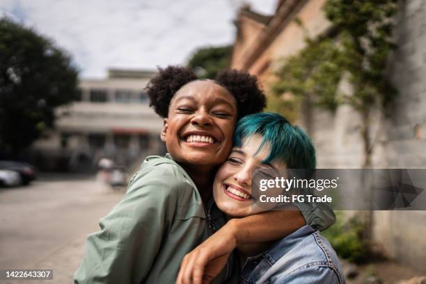 retrato de amigos abrazados en la calle - a la última moda fotografías e imágenes de stock
