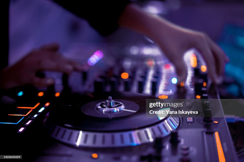 American DJ working with sound, spinning turntable records at a night club party