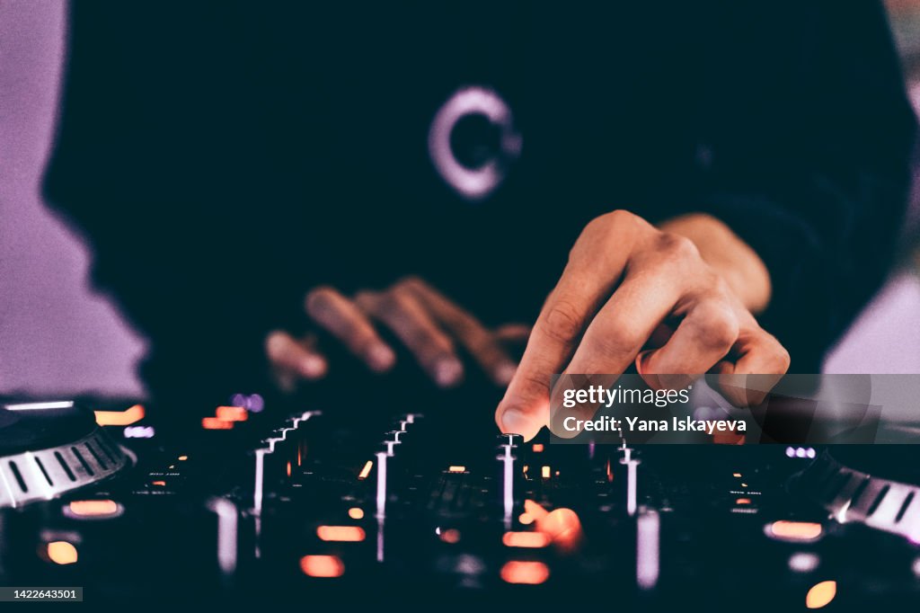 American DJ working with sound, spinning turntable records at a night club party