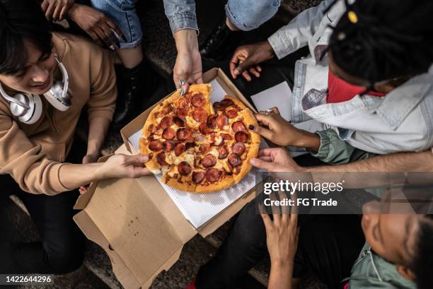 hände pflücken pizzascheiben - pepperoni pizza overhead stock-fotos und bilder