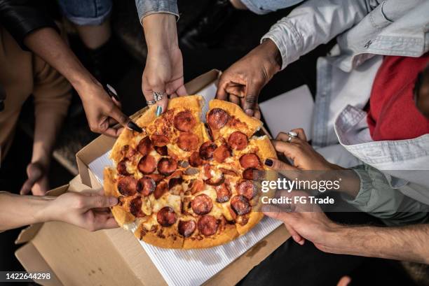 hands picking pizza slices - pizza share bildbanksfoton och bilder