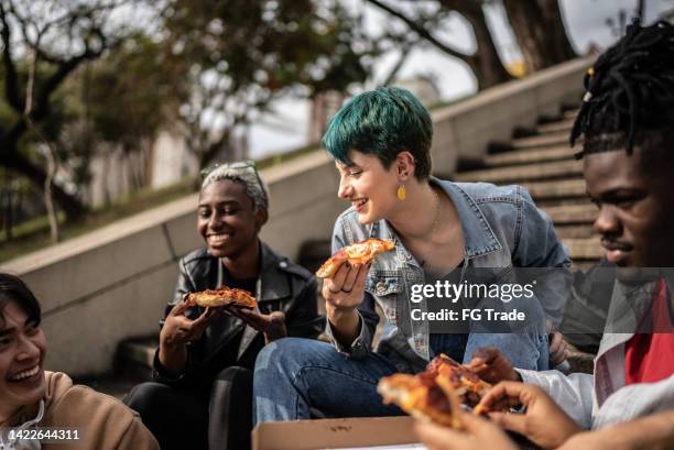 freunde essen pizza im park - alternative lifestyle stock-fotos und bilder