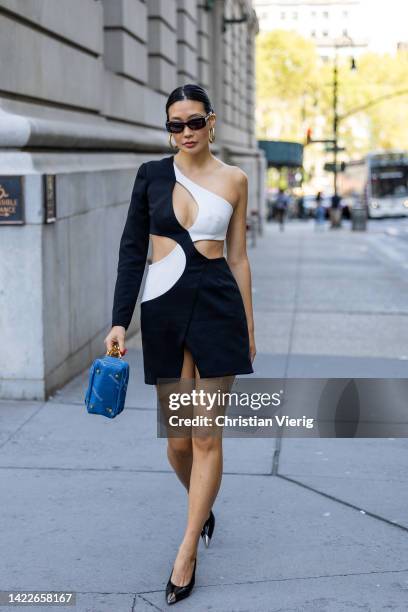 Guest wearing black white cut out dress, blue bag, heels outside PatBO on September 10, 2022 in New York City.