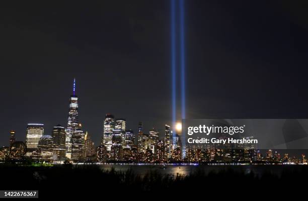 The full Harvest Moon rises behind the Tribute in Light as it is illuminated over lower Manhattan and One World Trade Center one day before the 21st...