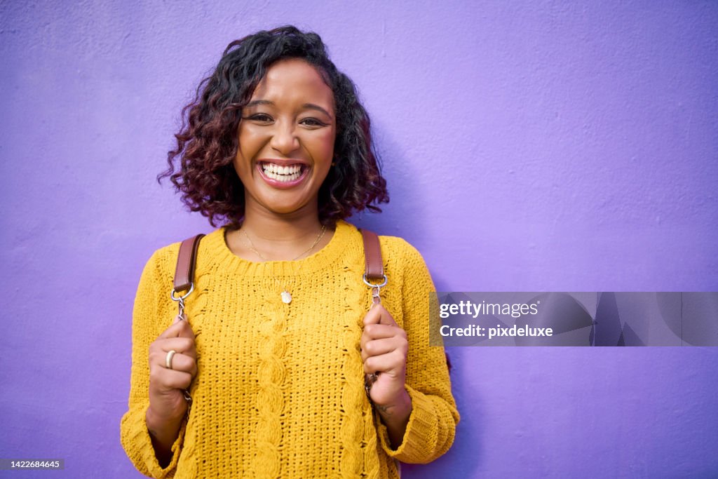 Happy, funky and retro portrait of gen z woman or student on a purple background wall mockup. Nlack woman with backpack big smile and fun, vibrant style enjoying her weekend, holiday or school break