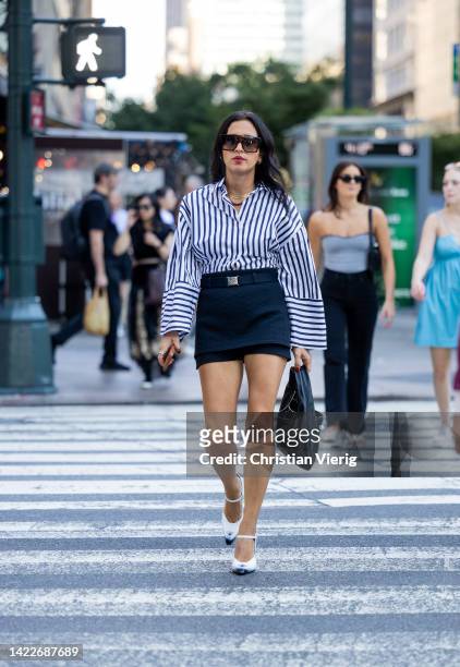 Guest wearing mini skirt, striped button shirt, black pants outside Dion Lee on September 10, 2022 in New York City.