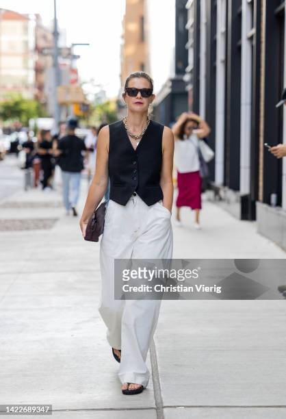 Guest wearing white pants, black vest outside Tibi on September 10, 2022 in New York City.