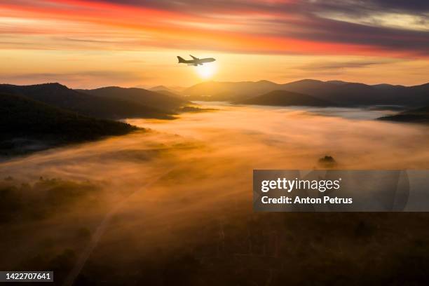 airplane over misty mountains at dawn - sonnenuntergang sonnenaufgang landschaft stock-fotos und bilder