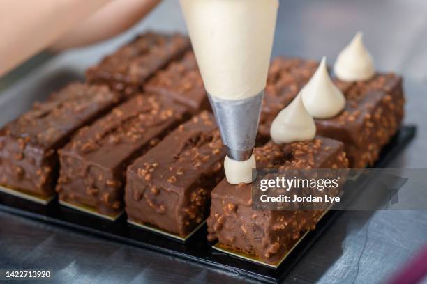 chef decorating chocolate cake with icing bag - pâtissier photos et images de collection