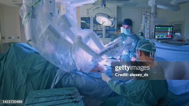 surgeon doing laparoscopic surgery in hospital with a medical robot - surgical robot stock pictures, royalty-free photos & images