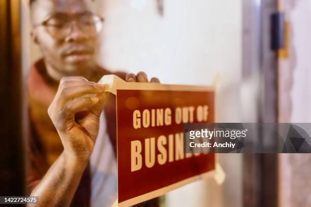 cropped shot of a man holding up a "going out of business" sign in his store - going out of business stock pictures, royalty-free photos & images