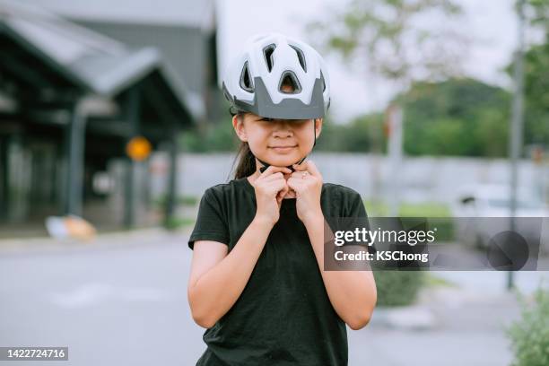 happy asian teenage girl putting cycle helmet - teenager cycling helmet stock pictures, royalty-free photos & images