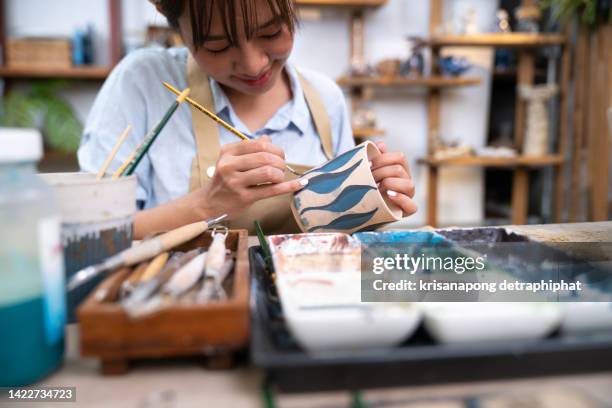 woman coloring handmade ceramic using brush and color,workshop production of ceramic tableware product painting - painting pottery stock pictures, royalty-free photos & images