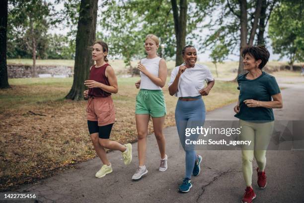 female friends jogging in park - mixed age range stock pictures, royalty-free photos & images