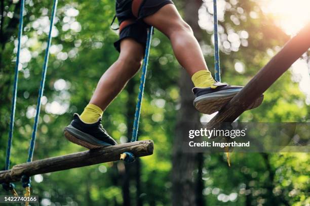 teenage boy walking in the high ropes course in a forest - ziplining stock pictures, royalty-free photos & images