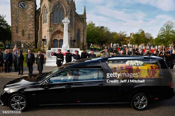 People gather in tribute as the cortege carrying the coffin of the late Queen Elizabeth II passes by on September 11, 2022 in Ballater, United...