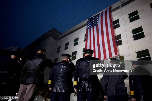 Members of the military and first responders stand in salute as an American flag is unfurled on the side of the Pentagon to commemorate the 21st...