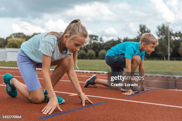 two athletic children working hard on the running track - running netherlands stockfoto's en -beelden