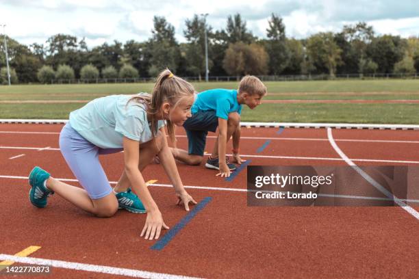 two athletic children working hard on the running track - kids track and field stock pictures, royalty-free photos & images