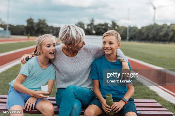 leichtathletik-mutter lauftrainerin mit ihren kindern nach einer trainingseinheit - soccer mum stock-fotos und bilder