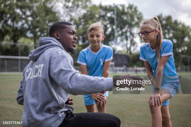 soccer football coach with two children during a training session - mens soccer team training session stockfoto's en -beelden
