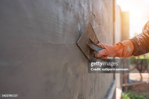 construction workers plastering cement on the construction of the wall on the construction site. - herbouwen stockfoto's en -beelden