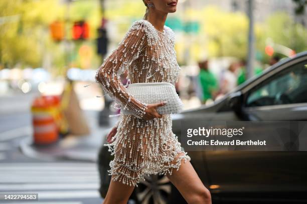 Leonie Hanne wears silver and diamonds BB logo earrings from Balenciaga, a beige tulle with embroidered white pearls long sleeves / cropped top, a...