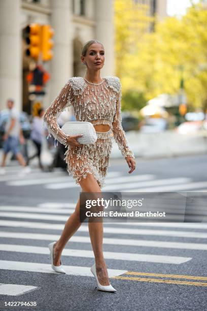 Leonie Hanne wears silver and diamonds BB logo earrings from Balenciaga, a beige tulle with embroidered white pearls long sleeves / cropped top, a...