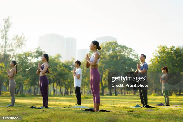 group of six people mixed age people making yoga pose in public park in city for fitness, sport, yoga and healthy lifestyle concept - yoga outdoor stock pictures, royalty-free photos & images