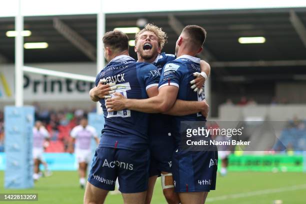 Luke James of Sale Sharks celebrates scoring their side's second try with teammates Tom Roebuck and Gus Warr during the Gallagher Premiership Rugby...