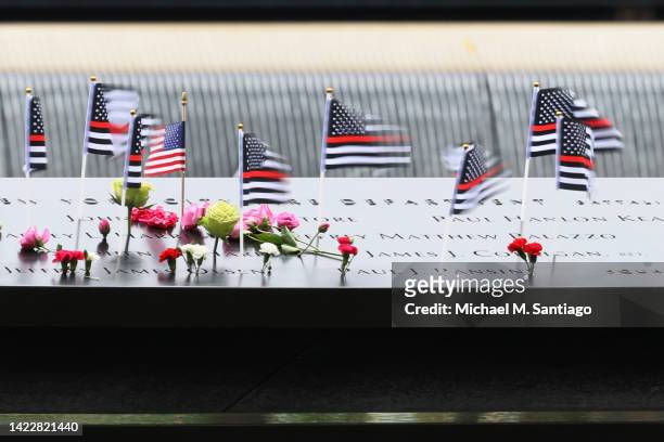 American flags wave in the wind as they sit on the names of victims of the 9/11 terror attack in the North Tower Memorial Pool during the annual 9/11...