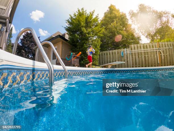 mixed race six year old boy walking beside swimming pool - backyard pool fotografías e imágenes de stock